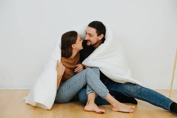 Retrato de um casal de meia idade sentado no chão envolto em cobertor, beijando — Fotografia de Stock