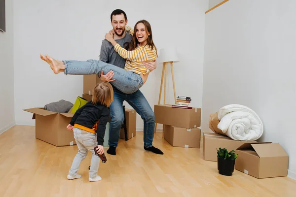Glad ung familj firar flytt till ett nytt hem, ha kul tillsammans. Stockfoto