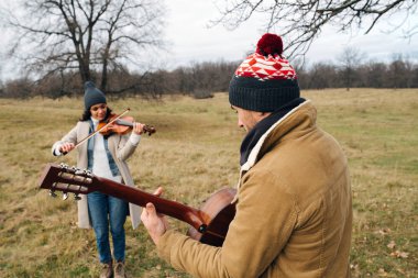 Sonbaharda çayırda çalan sıcak giyimli müzisyenlerin düeti