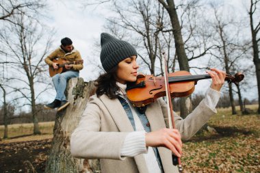 Bir kemancı ve gitarist düeti güzel bir sonbahar ormanında müzik çalıyor.