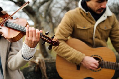Sonbaharda kırsalda müzik çalan sıcak giyimli iki müzisyene yakın durun.