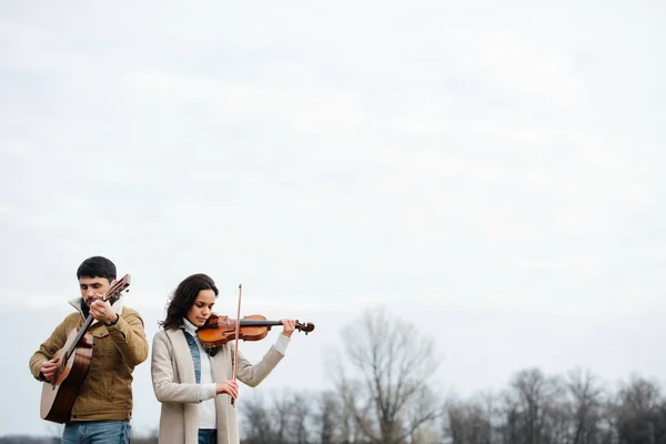 Dos músicos calurosamente vestidos que tocan en el campo en otoño sobre el cielo brillante — Foto de Stock