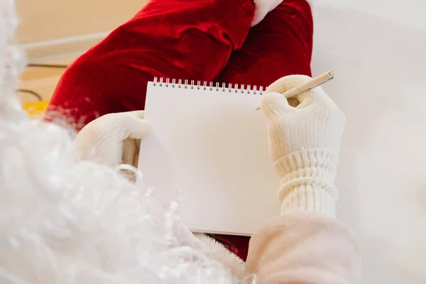 Detailní záběr. Santa Claus píše dopis do zápisníku. Místo pro text — Stock fotografie