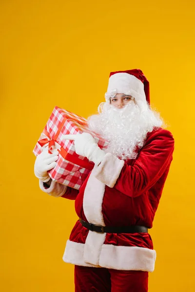 Papai Noel aponta um dedo para algo à direita, ele segurando um grande presente — Fotografia de Stock
