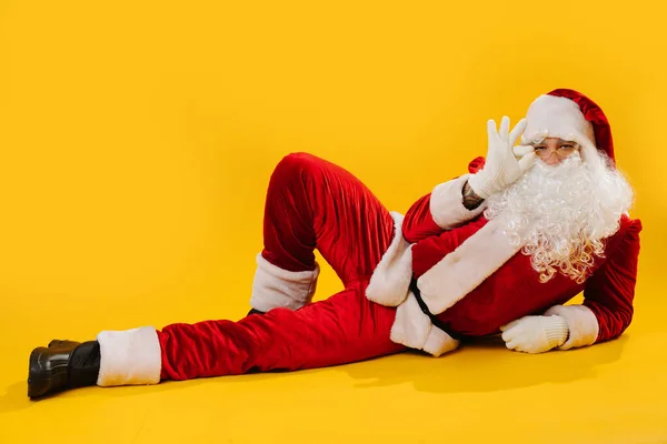 Święty Mikołaj leżący na podłodze w bezczelny sposób, trzymając okulary — Zdjęcie stockowe