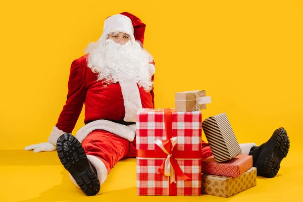 Santa Claus s mnoha dary v krabicích sedí na podlaze — Stock fotografie