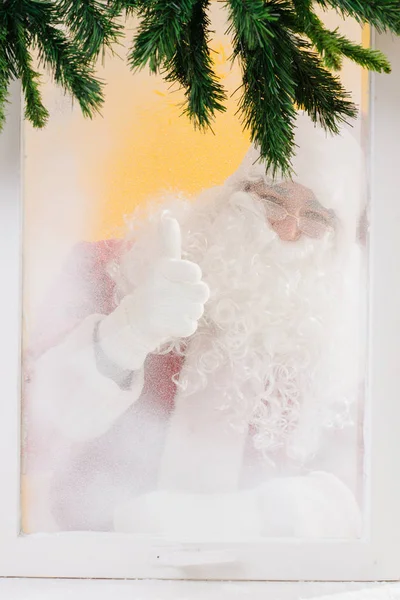 Santa is looking at us through the window and thumbs up. Merry Christmas. — Stock Photo, Image