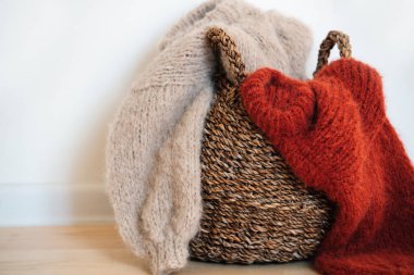 Hasır çanta, odada çok renkli örgü süveterler var..