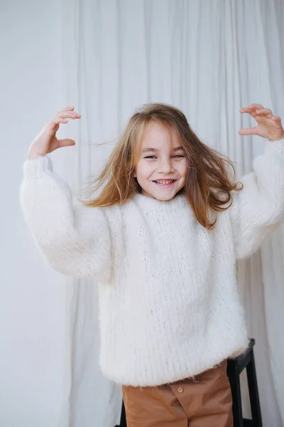Sorrindo menina com o cabelo bagunçado apenas colocar em suéter de malha macio branco . — Fotografia de Stock
