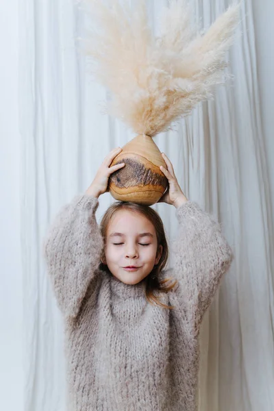 一个小女孩玩椰子瓶的肖像，花瓶里有麦片花束. — 图库照片