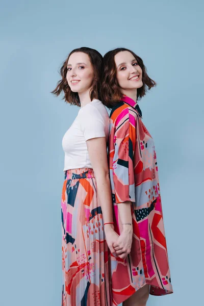 Two twin sister in a bright image on a blue background — Stock Photo, Image