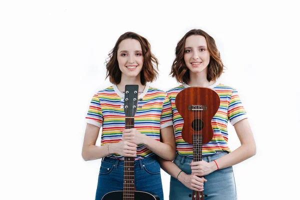 Two twin sisters with musical instruments in their hands. — Stock Photo, Image
