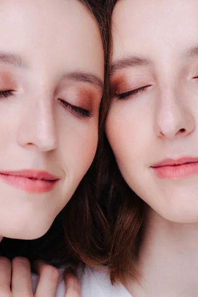 Two faces of twin sisters with nude make-up.