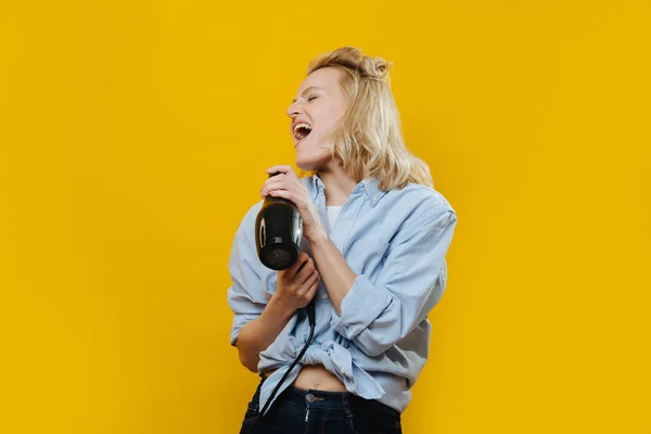 Blonde barbeiro senhora cantando em um secador de cabelo, usá-lo como microfone — Fotografia de Stock