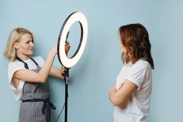 Леди парикмахер фотографирует клиента с помощью кольцевой лампы — стоковое фото