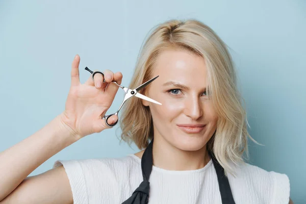 Stylische blonde Friseurin mit offener Schere neben ihrem Gesicht — Stockfoto