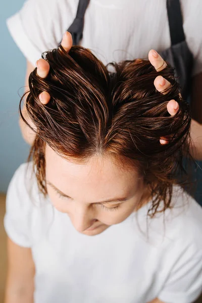 Cabeleireiro correndo dedos através do cabelo do cliente para prepará-lo para aparar . — Fotografia de Stock