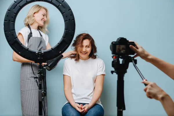 Glückliche Stylistin trocknet dem Kunden die braunen Haare, während das Foto gemacht wird — Stockfoto