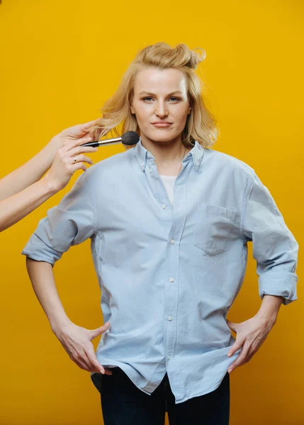 Donna attraente in posa per una foto mentre le mani che applicano il trucco sul suo viso — Foto Stock