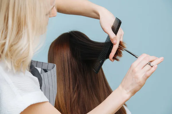 Cabeleireiro senhora aparar o cabelo do cliente termina sobre azul — Fotografia de Stock