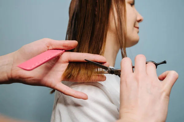 Mulheres cabeleireiro mãos aparar o cabelo do cliente sobre fundo azul . — Fotografia de Stock