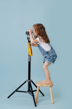 Küçük kız bir fotoğraf makinesi tutuyor ve fotoğraf çekiyor.