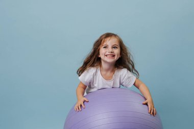 Mavi gözlü kıvırcık kız leylak fitness topuyla gülüyor..