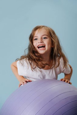 blue-eyed girl plays with violet fintes ball. clipart