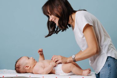 Anne bebeğiyle konuşur ve altını değiştirir.