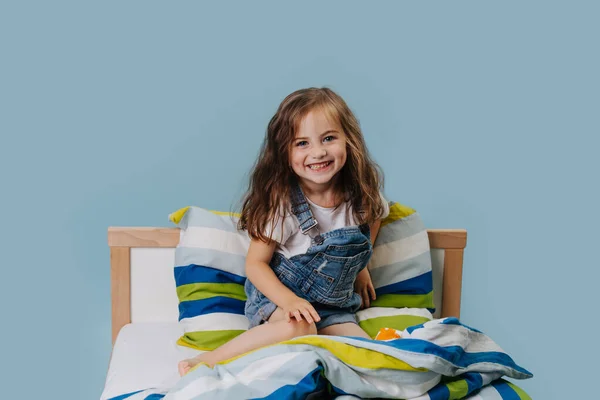 Happy smiling girl plays in her bed. — Stock Photo, Image