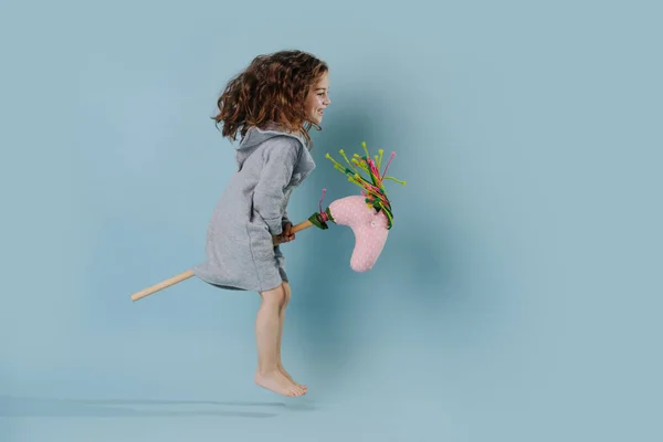 La chica rizada juega con el caballo palo . — Foto de Stock