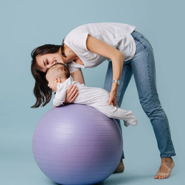 Loving mother does exercises with her infant son — Stock Photo, Image