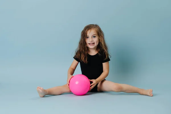 Little girl gymnast plays with a pink ball. — Stock Photo, Image