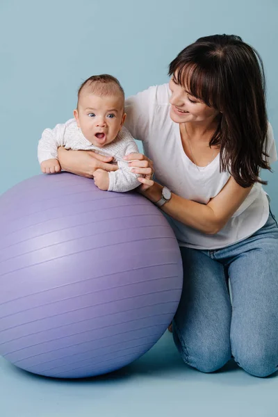 Young mother is engaged in exercises with her infant son — Stock Photo, Image