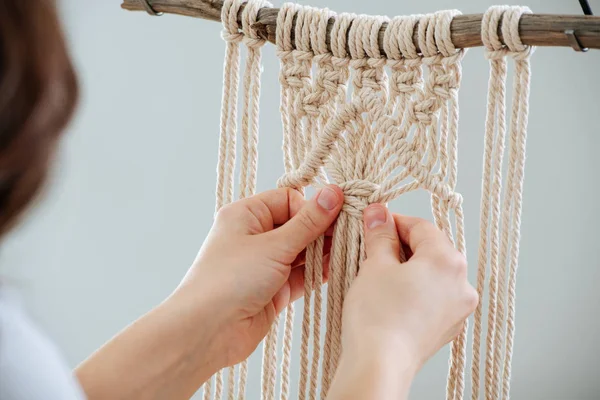 Ambachtelijke vrouw weven touwen, het creëren van een macrame banner. van achteren. — Stockfoto