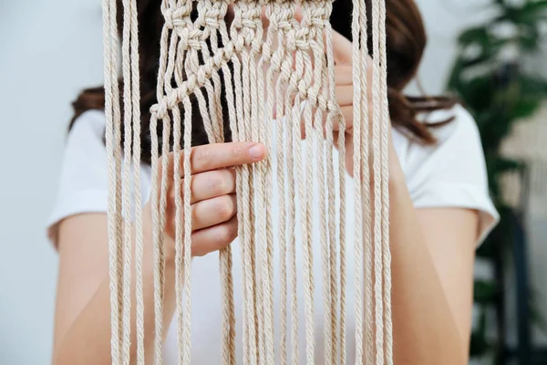 Craftswoman werken aan een onafgewerkte macrame stuk, weven touwen. — Stockfoto