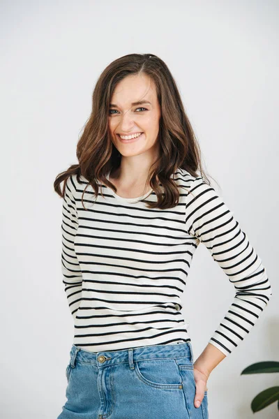 Portrait of a cheerful brunette with long voluminous hair, casually dressed.