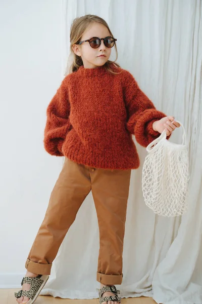 Модна маленька дівчинка в темно-оранжевому в'язаному светрі з сумкою — стокове фото