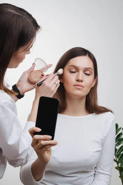 Estilista feminina aplicando pó de configuração no rosto do cliente — Fotografia de Stock