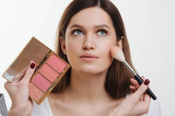 Mãos estilistas aplicando blusher no rosto do cliente em uma sala brilhante — Fotografia de Stock