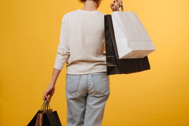 Woman in old loose comfortable jeans carrying bunch of shopping paper bags