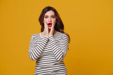 Surprised middle aged brunette with vibrant red lipstick in a striped shirt