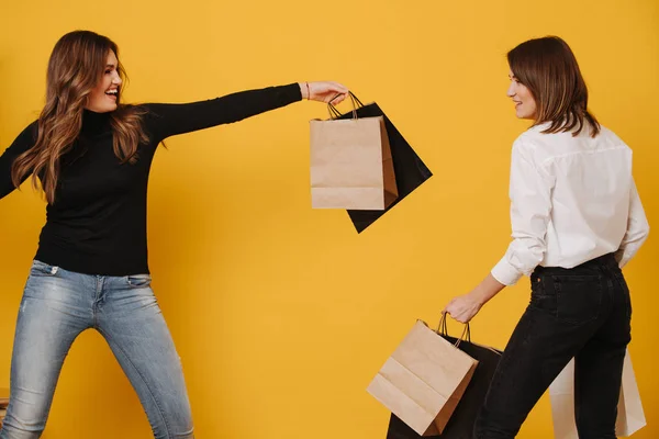Two happy female friends happy and uplifting after shopping over yellow