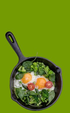 Tavada yumurta, ıspanak, brokoli ve domatesli yeşil arka plan.