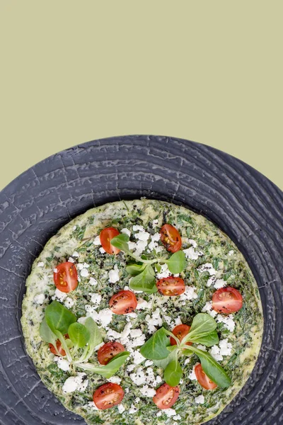 Omelet con verdure, spinaci, pomodori e formaggio su un piatto strutturato sopra verde — Foto Stock