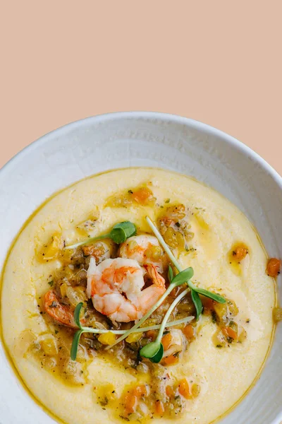 Soupe à la purée chaude aux crevettes et légumes dans une assiette blanche sur fond rose — Photo