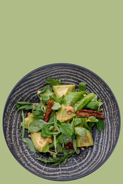 Zelený salát na talíři. Špenátové listy s avokádem, kešu, ovocem. — Stock fotografie