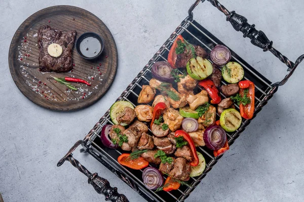 Assorted delicious grilled meat with vegetables next to a steak on a plate — Stock Image Assorted delicious grilled meat with vegetables next to a steak on a plate Stock Image
