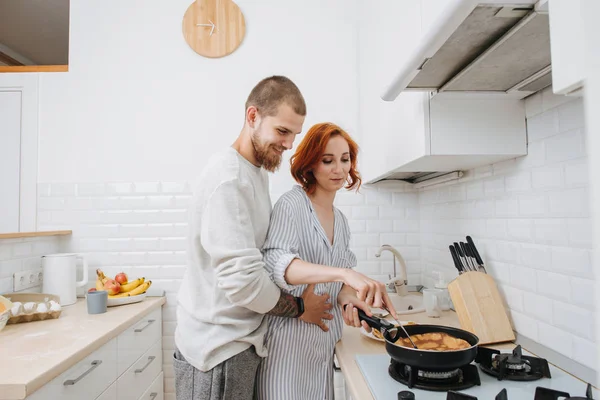 Happy married couple cooking together, frying dish on a pan — Stock Photo, Image