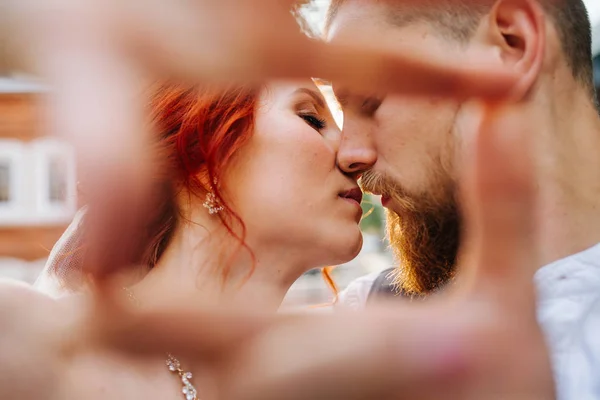 La novia y el novio besándose mientras hacen un marco con sus manos — Foto de Stock